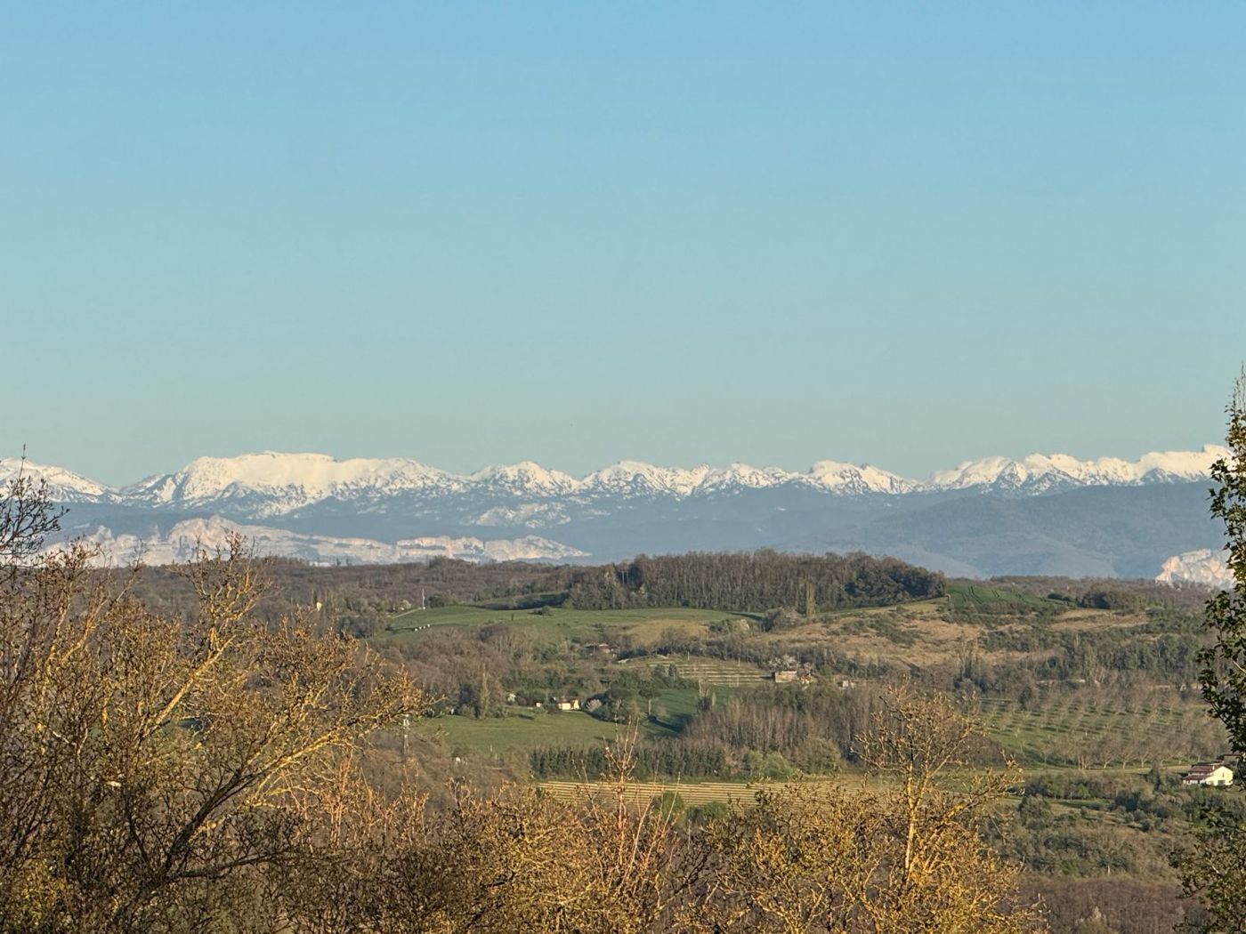 Les collines et la chaîne des Alpes enneigée à l'horizon, en fin de journée
