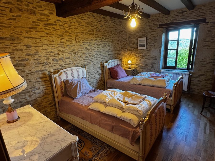 Chambre aux deux lits anciens peints et mur en pierre