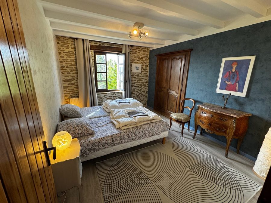 Chambre bleue avec tableau, commode marquetée et fenêtre sur le jardin