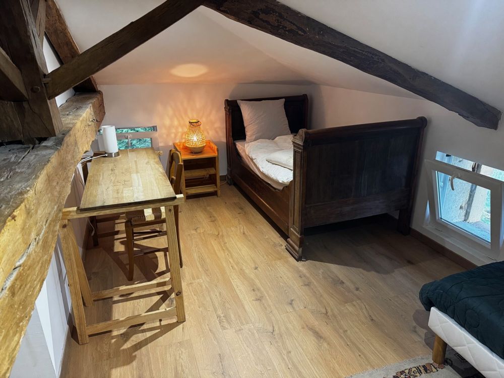 Chambre aux poutres apparentes, lit bateau en bois et bureau