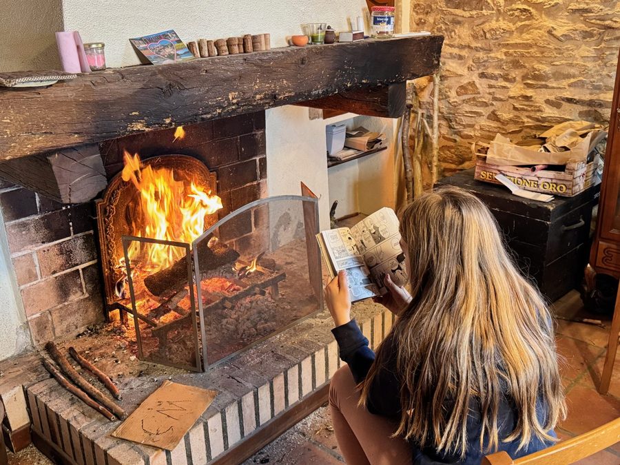 Une jeune fille lit au coin du feu dans la cheminée en pierre