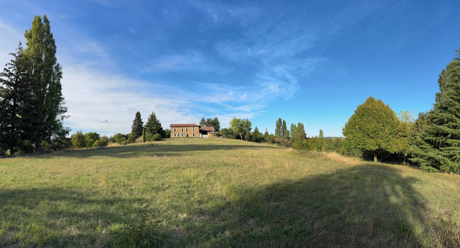 La prairie et la maison au loin, sous un grand ciel bleu