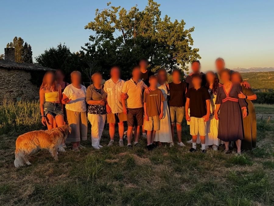 Une famille de trois générations dans la prairie au coucher du soleil, avec le chien
