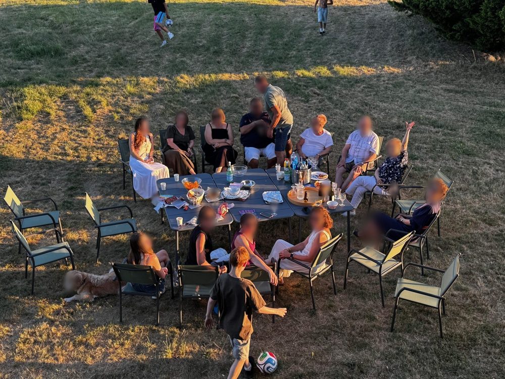 Un groupe attablé dans la prairie fait signe vers l'appareil photo