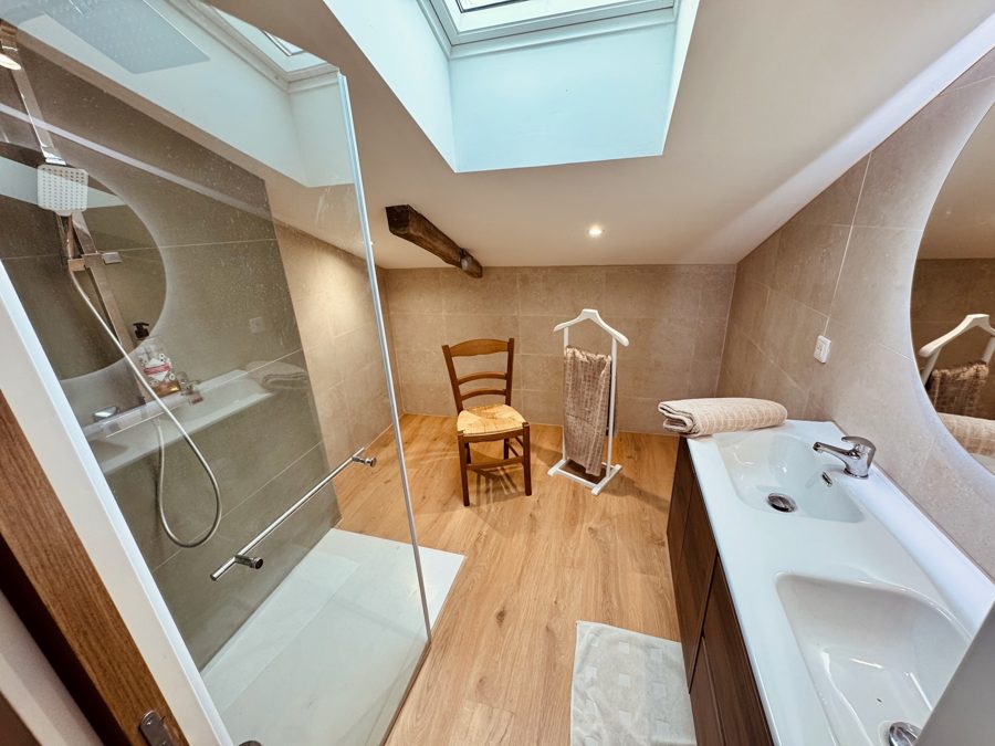 Salle d'eau à l'étage avec grande douche vitrée et vasque, velux