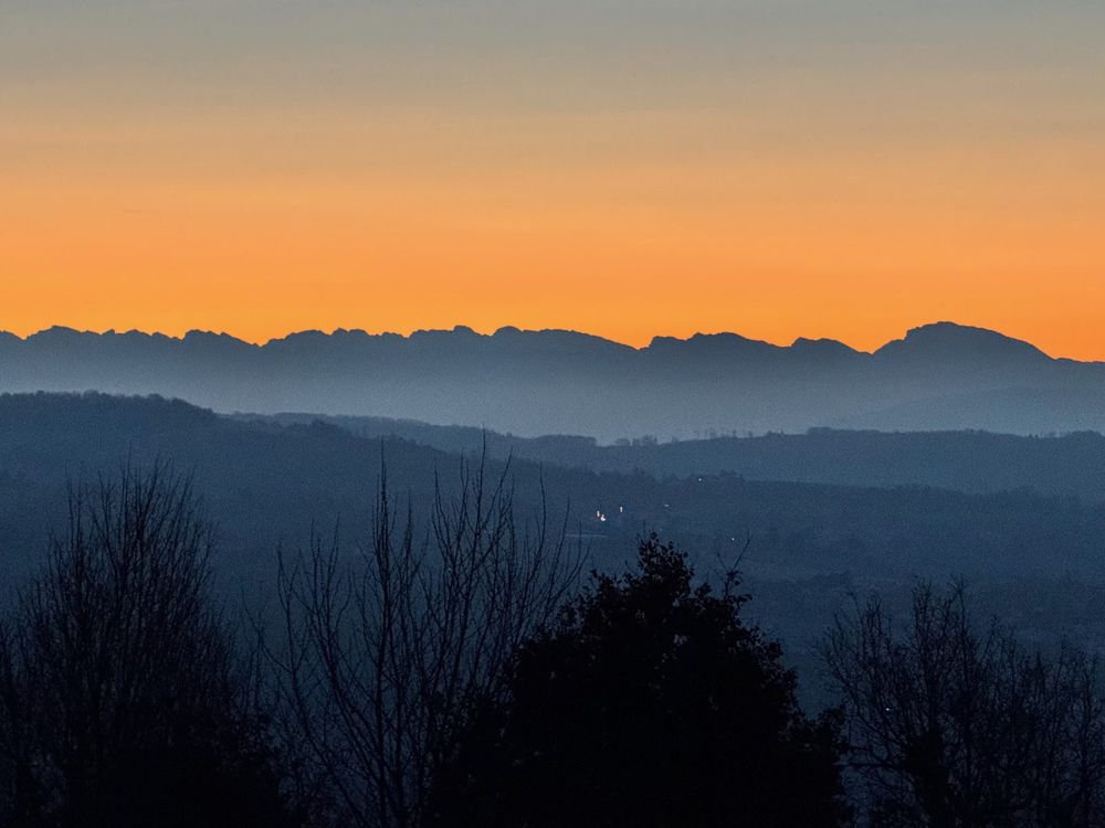 Les crêtes du Vercors en silhouette sur un ciel orangé à l'aube