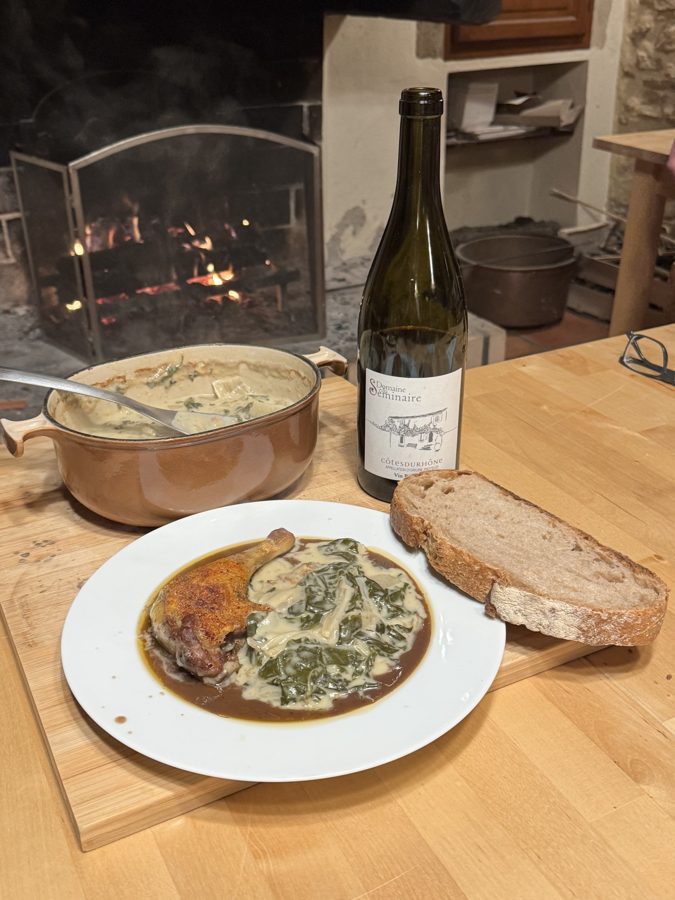 Assiette, pain de campagne et bouteille de vin sur la table, devant la cheminée allumée