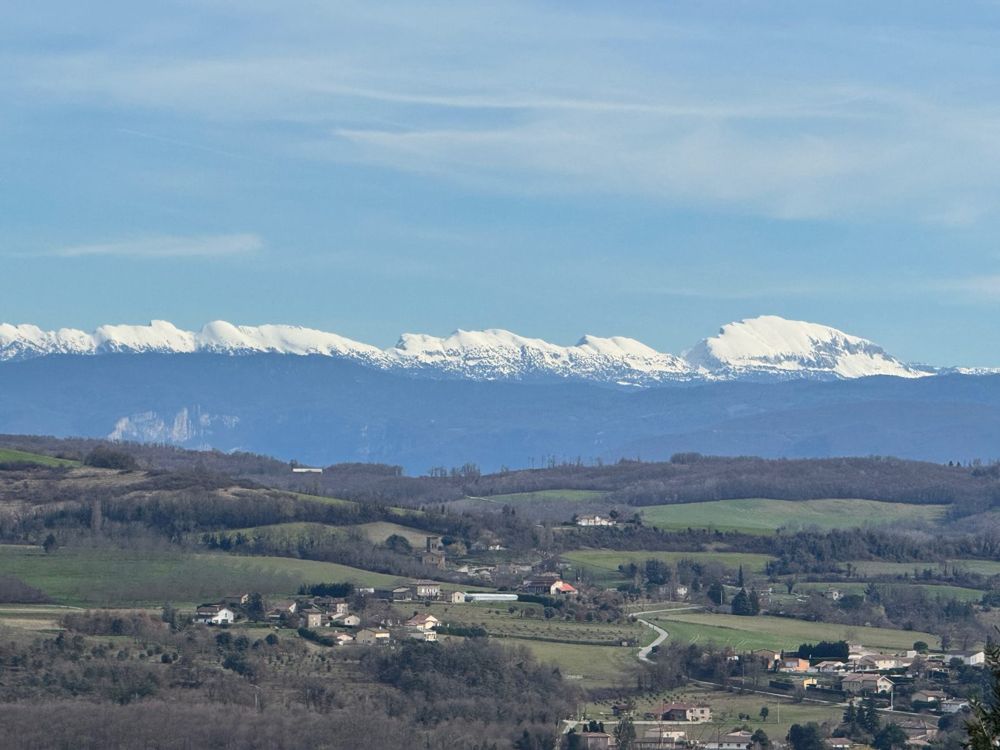 Les crêtes enneigées du Vercors au-dessus de la vallée et des villages, sous un ciel bleu