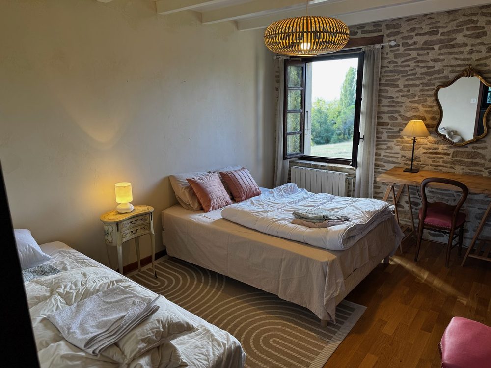 Chambre lumineuse au lit double, fenêtre ouverte sur la campagne
