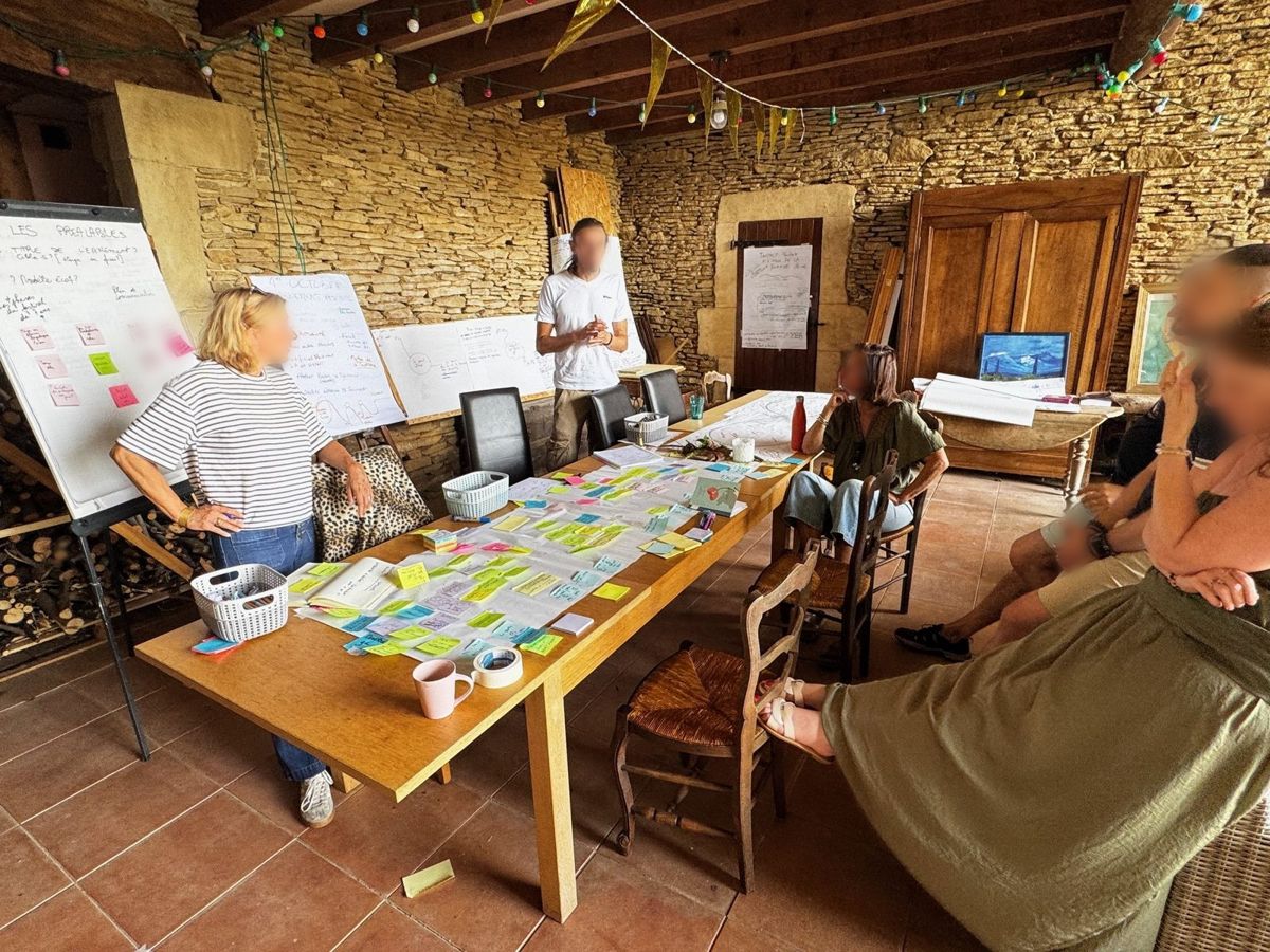 Restitution d'atelier sous l'auvent de la cour, groupe autour d'une grande table couverte de post-it