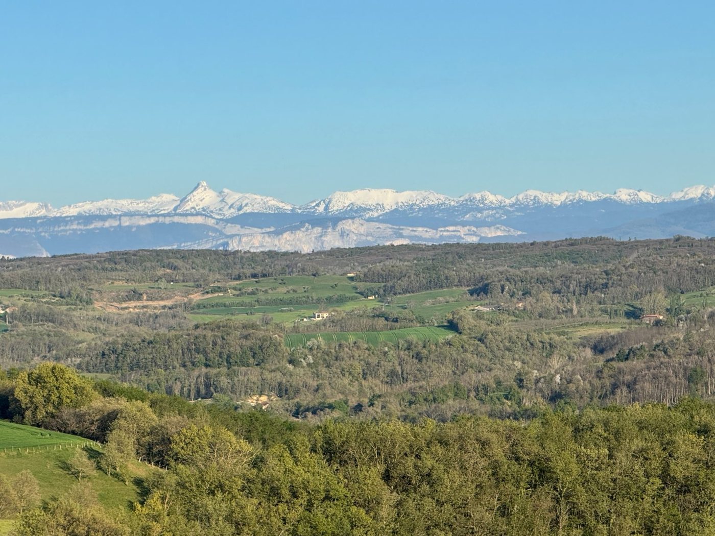 Collines printanières et sommets enneigés à l'horizon, vus depuis le parc